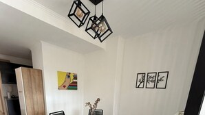 A dining area with a glass table and black chairs, a white cabinet, and a painting on the wall.