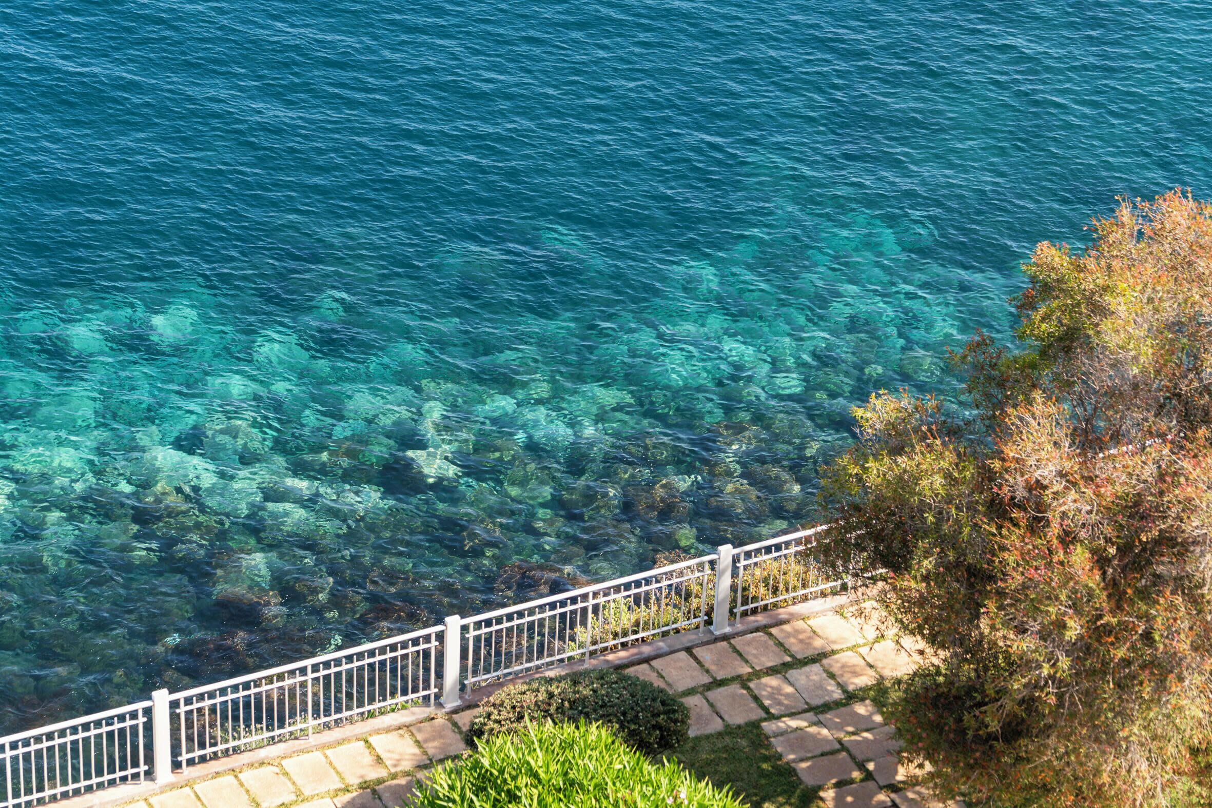 A clear view of a lake with a stone pathway and white railing along the edge.