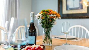 Ett matbord med en vinflaska, ett glas, en vas med blommor och en tallrik med mat.