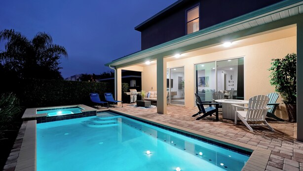 Une piscine avec un espace patio, du mobilier d’extérieur et un coin salon abrité.