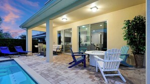 Un patio extérieur abrité avec une piscine, des chaises longues et un espace repas.