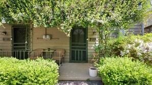 Una casa con puerta verde, un porche con sillas y un letrero que dice 'Bears Den'.