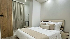 Une chambre avec un grand lit, un plancher en bois, une porte en bois et un miroir.