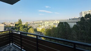 Un balcon offrant une vue sur le paysage urbain, avec des bâtiments et des arbres.