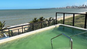 Ein Pool auf dem Dach mit Blick auf das Meer und die Skyline der Stadt.