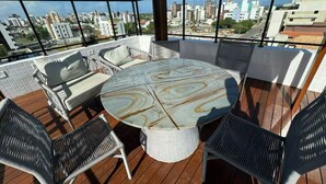 Eine Dachterrasse mit rundem Tisch und Stühlen, die einen Blick auf die Stadt bietet.