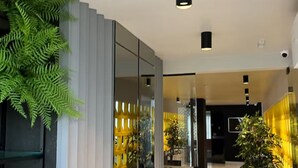 Eine moderne Hotelhalle mit Glastüren, einer Rezeption und Zimmerpflanzen.