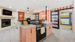Eine moderne Küche mit einer zentralen Kochinsel, einem eingebauten Backofen und einem Fernseher über dem Kamin.