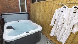 A hot tub in a backyard with a wooden fence and a window.