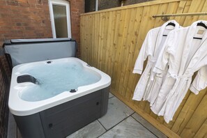 A hot tub in a backyard with a wooden fence and a window. - Beautiful 3-Bed Home with Hot Tub in Ross-on-Wye (Ross-on-Wye)