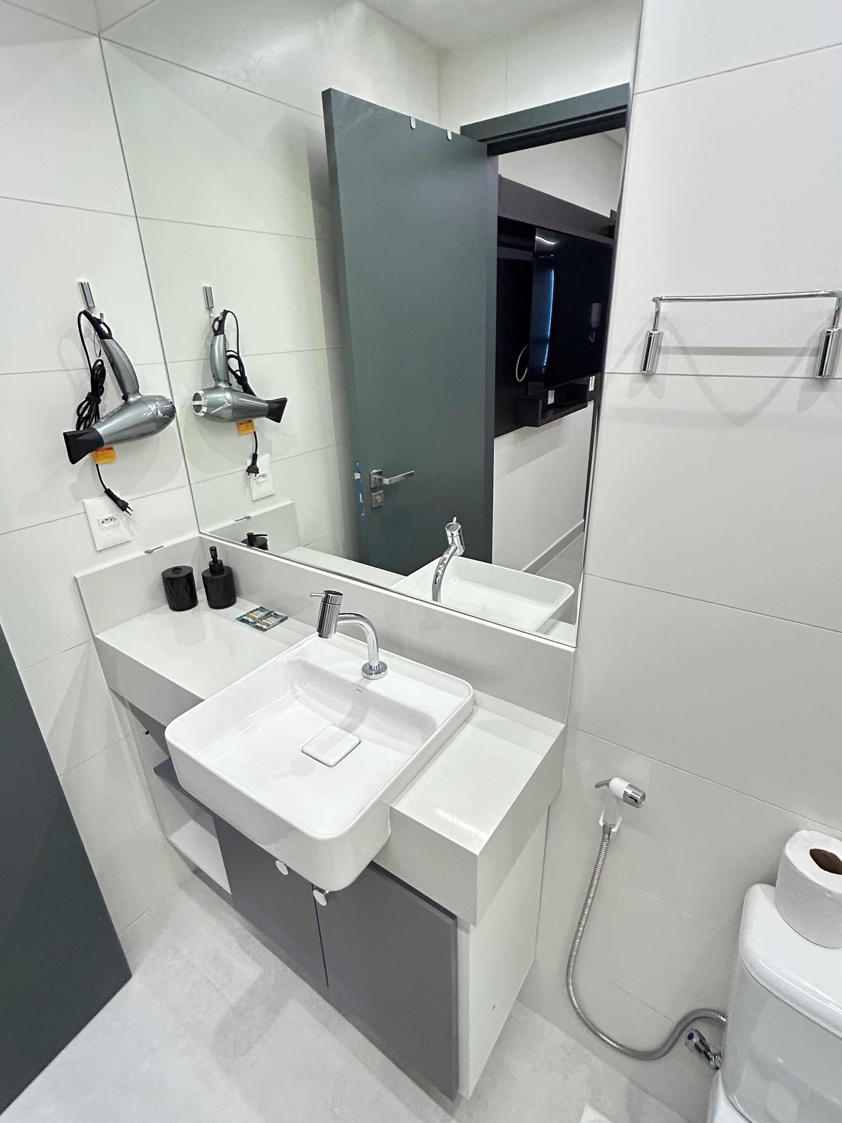 A modern bathroom with a white sink, a mirror, and a shower.