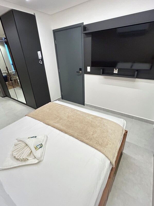 Een slaapkamer met een bed, een kledingkast en een ingebouwde tv-plank.