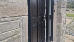 A stone exterior with a black door and a small porch. - A large 4 bed family home to make great memories in the West Coast of Ireland. (Westport)