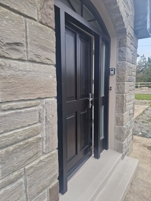 A stone exterior with a black door and a small porch. - A large 4 bed family home to make great memories in the West Coast of Ireland. (Westport)
