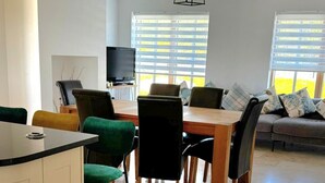 A modern living room with a dining area, a TV, and a sofa with patterned cushions. - A large 4 bed family home to make great memories in the West Coast of Ireland. (Westport)