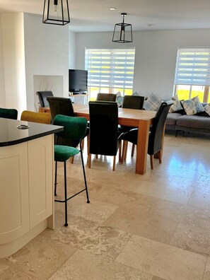 A modern living room with a dining area, a TV, and a sofa with patterned cushions. - A large 4 bed family home to make great memories in the West Coast of Ireland. (Westport)