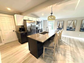 Una cucina moderna con isola centrale, elettrodomestici in acciaio inossidabile e un lampadario.