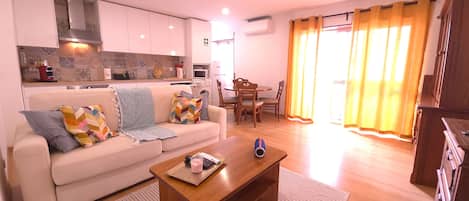 A compact living space with a kitchenette, a sofa, a coffee table, and a dining area.
