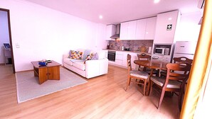 A compact living space with a kitchenette, a dining area, and a sofa. - Caparica Escape By Gt House (Almada)