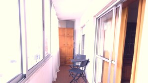 A narrow corridor with a table and chairs, large windows, and a wooden cabinet. - Caparica Escape By Gt House (Almada)