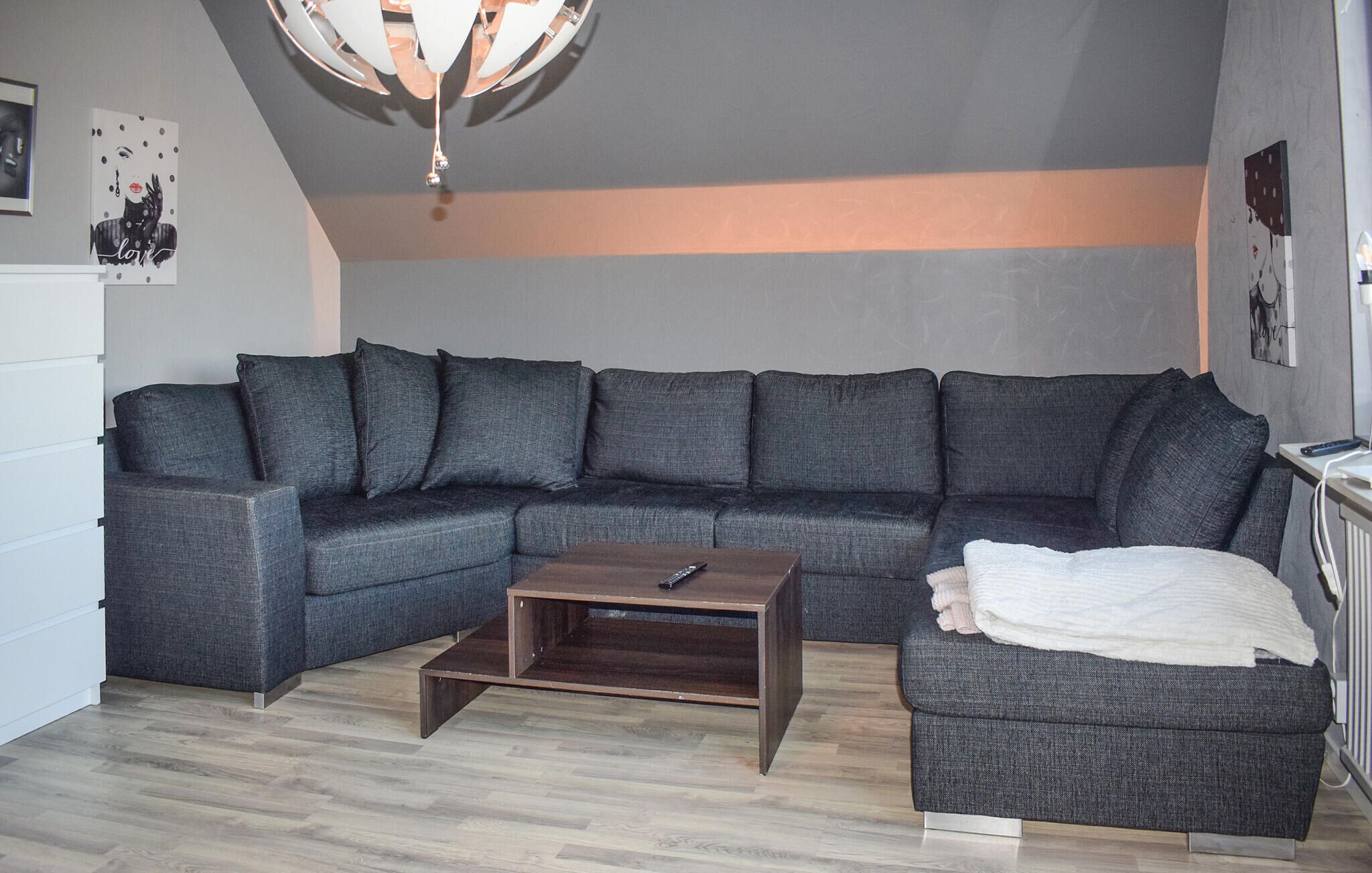 A modern living room with a grey sectional sofa, a wooden coffee table, and a grey armchair.