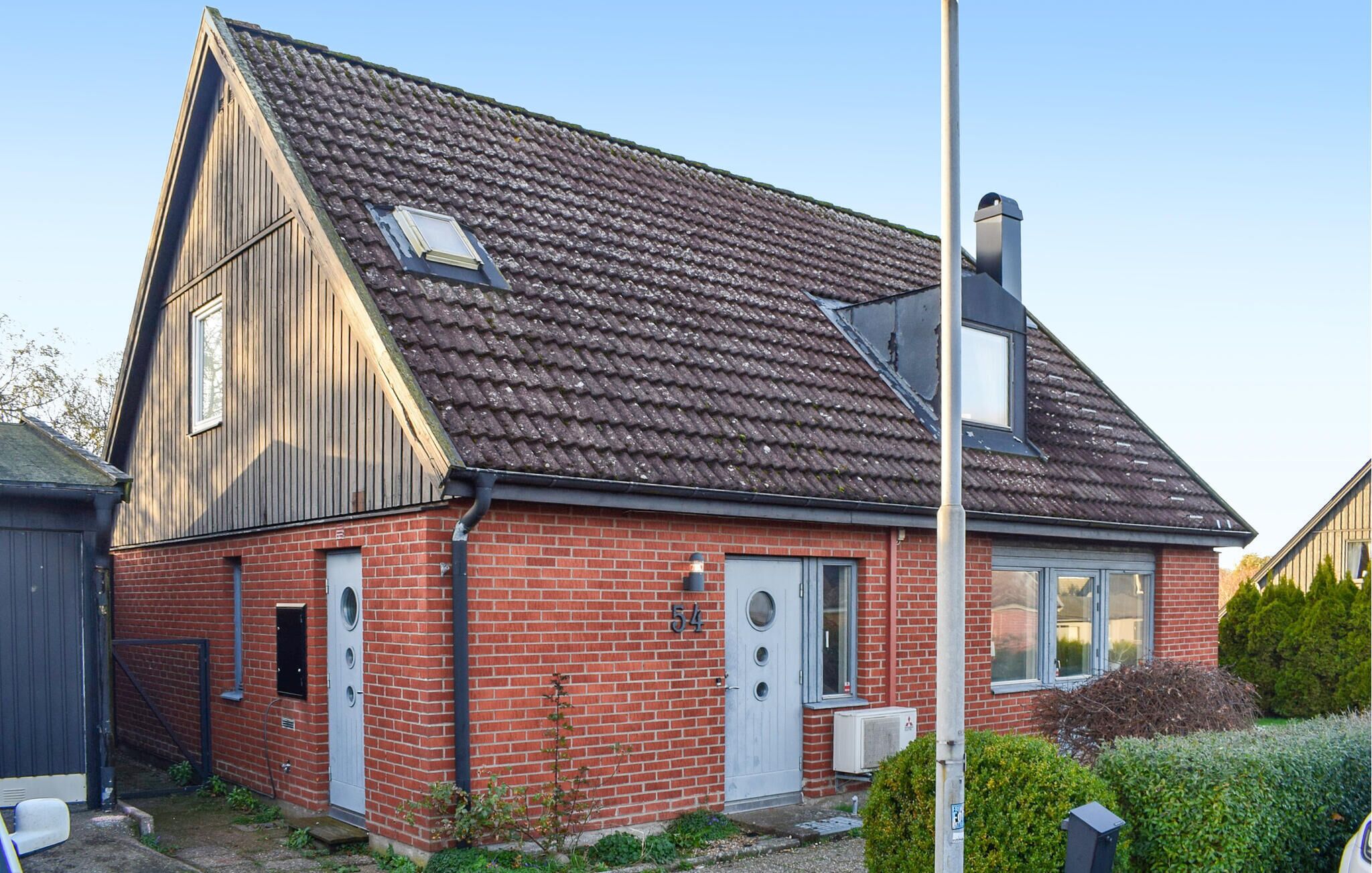 A red brick house with a gabled roof, a chimney, and a small attached garage.