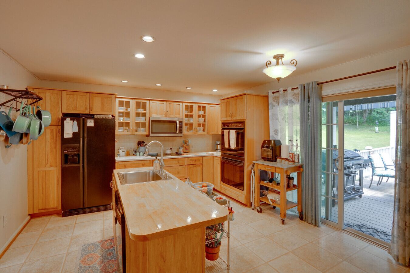 Une cuisine spacieuse avec des meubles en bois, un îlot central et une porte-fenêtre coulissante donnant sur un patio.