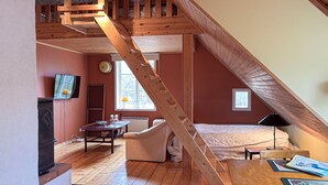 Un dormitori tipus loft amb una escala de fusta, un llit, un escriptori i una televisió.
