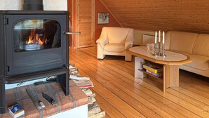 Una habitació acollidora amb una estufa de llenya, un sofà, una taula de cafè i una prestatgeria.