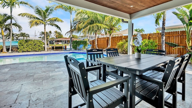 An outdoor patio with a pool, wooden deck, and a dining table with chairs. - Waterfront Oasis • Pool • Ocean Access. near beach.near golf.pet friendly (Pompano Beach)