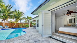 A modern house with a swimming pool, a bedroom with a bed and a ceiling fan, and a wooden fence in the backyard. - Waterfront Oasis • Pool • Ocean Access. near beach.near golf.pet friendly (Pompano Beach)