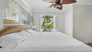 A bedroom with a large bed, a ceiling fan, and a view of a patio with outdoor furniture. - Waterfront Oasis • Pool • Ocean Access. near beach.near golf.pet friendly (Pompano Beach)
