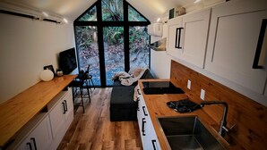 Una cocina moderna con suelo de madera, armarios blancos, un ventanal y vistas al exterior.