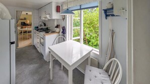 A compact kitchen with a white table and chairs, a stove, and a window with a view of greenery. - 2 bedroom amazing home in Fagerhult (Fagerhult)