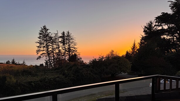 Un balcón con vista al atardecer, un lavamanos de piedra y una barandilla.
