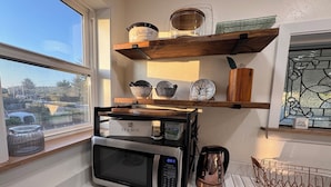 Una cocina con microondas, caja de té y hervidor en la encimera.