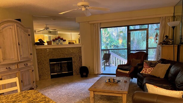 A living room with a fireplace, a dining area, and a view of the outdoors. - Riverfront 2-bedroom townhome in peaceful Homosassa with AC/Heat, Pool (Homosassa)