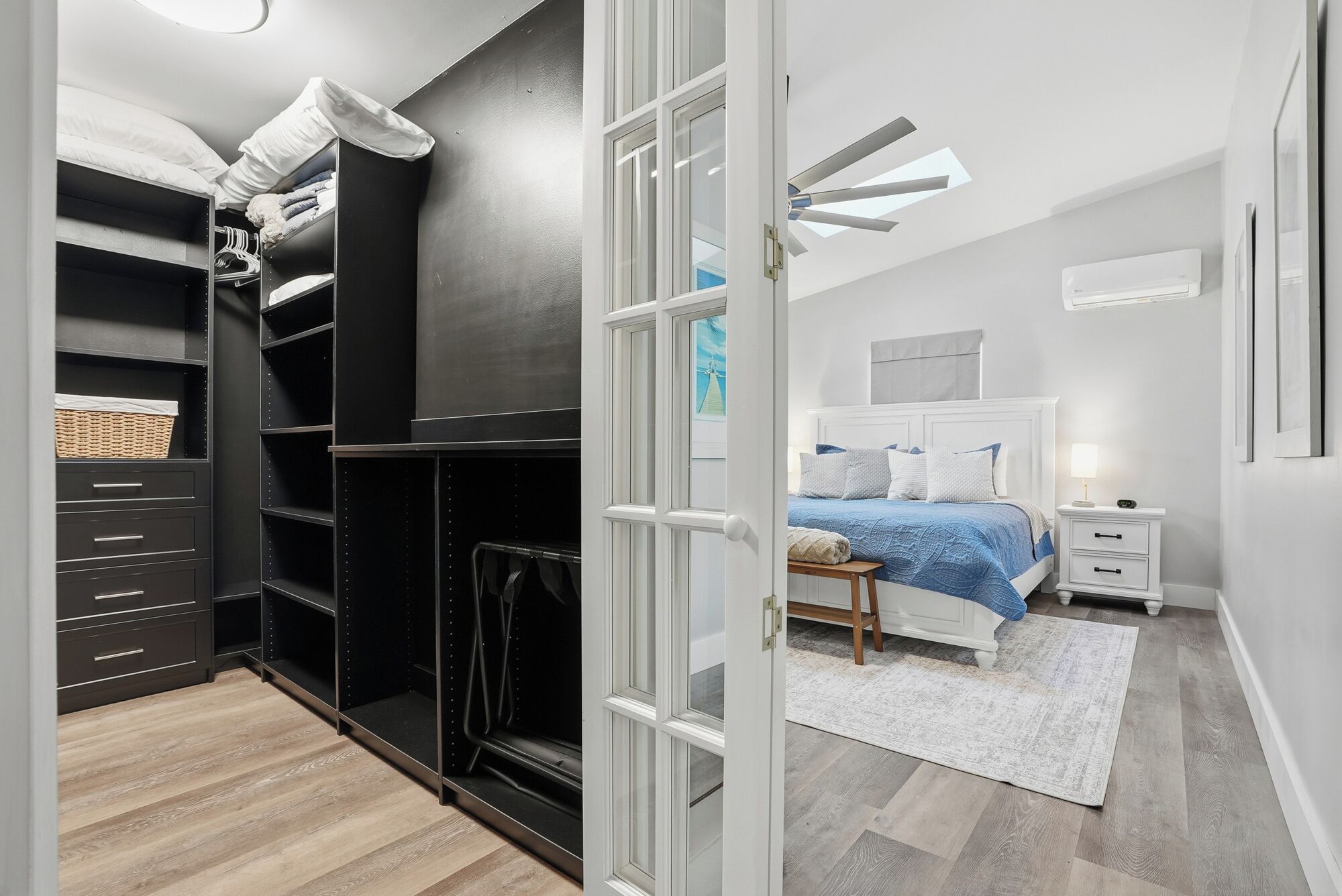Un dormitorio con cama, mesita de noche y un armario con estantes y espacio para colgar ropa.
