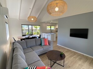 Ein modernes Wohnzimmer mit einem Ecksofa, einem runden Couchtisch und einem an der Wand befestigten Fernseher.