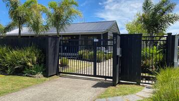 A gated property with a paved driveway leading to a building with a metal roof.