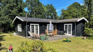 Ein schwarzes Haus mit Terrasse, Grill und Gartenmöbeln.