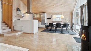 Une cuisine moderne avec des meubles en bois, un îlot central et un coin repas comprenant une table et des chaises.