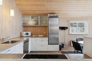 A compact kitchen with a stainless steel refrigerator, a microwave, and a sink. - Family-friendly holiday home with spa and sauna (Knebel)