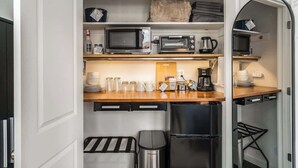 Een kleine keuken met een magnetron, broodrooster, koffiezetapparaat en een koelkast.