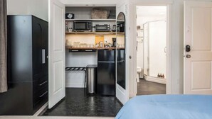 Een kleine hotelkamer met kitchenette, een bed en een badkamer.
