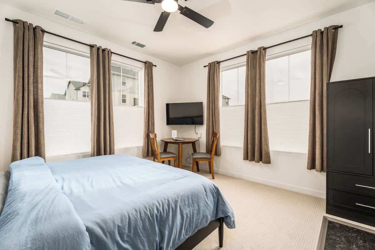 A bedroom with a bed, a television, a desk with two chairs, and a wardrobe.