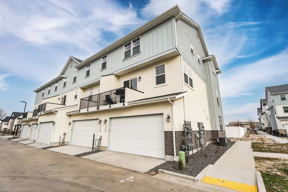 A multi-story residential building with a garage, a balcony, and a clear sky.