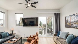 Ein modernes Wohnzimmer mit einer Couch, Sesseln, einem Couchtisch und einem Fernseher.