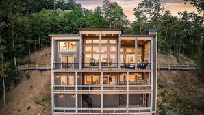 A multi-story modern house with large windows, a staircase, and a deck. - NEW CONSTRUCTION 4-bedroom with INCREDIBLE VIEWS minutes to Downtown Blue Ridge! (Mineral Bluff)