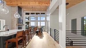 A modern kitchen with a central island, bar stools, and hanging pendant lights. - NEW CONSTRUCTION 4-bedroom with INCREDIBLE VIEWS minutes to Downtown Blue Ridge! (Mineral Bluff)